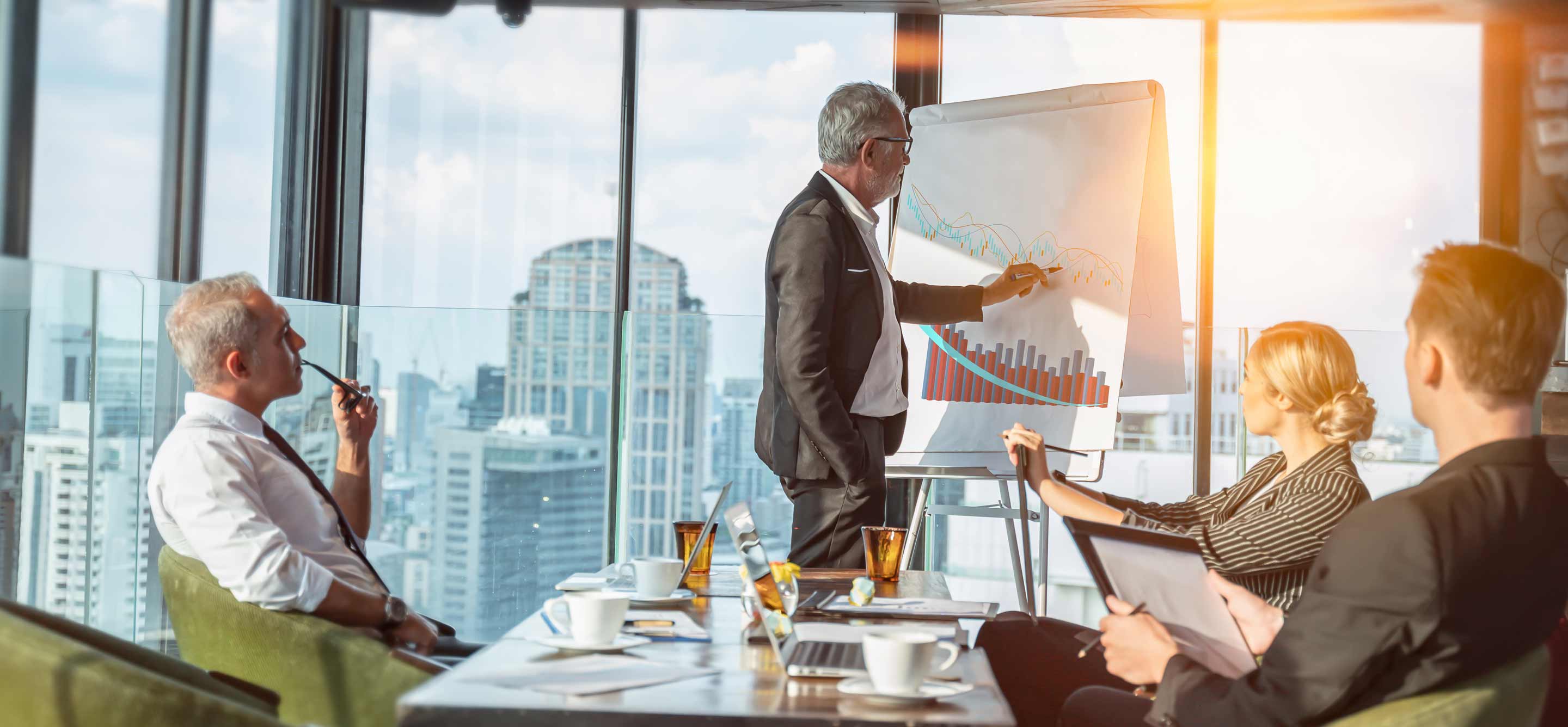 4 colleagues having a meeting in a room with a view of the skyline.